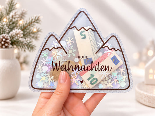 Schüttelkarte Weihnachten in Bergform mit dem Spruch „Frohe Weihnachten“, gefüllt mit Geldscheinen und Schneeflocken-Konfetti